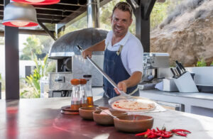 Chef cooking outdoors a veggie pizza