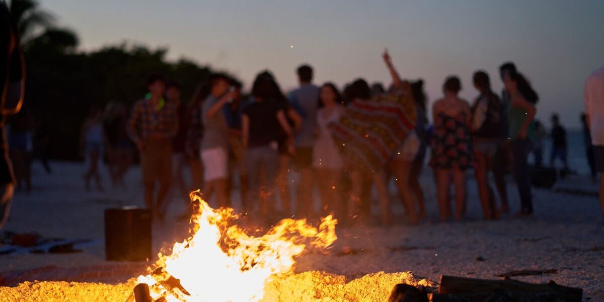 San Juan bonfire celebration on an Ibiza beach with people dancing at sunset