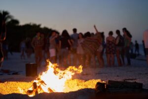 San Juan bonfire celebration on an Ibiza beach with people dancing at sunset