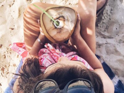 Beach recovery Girl drinking coconut water on the beach in Ibiza to rehydrate after a night out