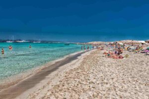 People relaxing on a quiet beach in Formentera under the sun, enjoying a peaceful summer day.