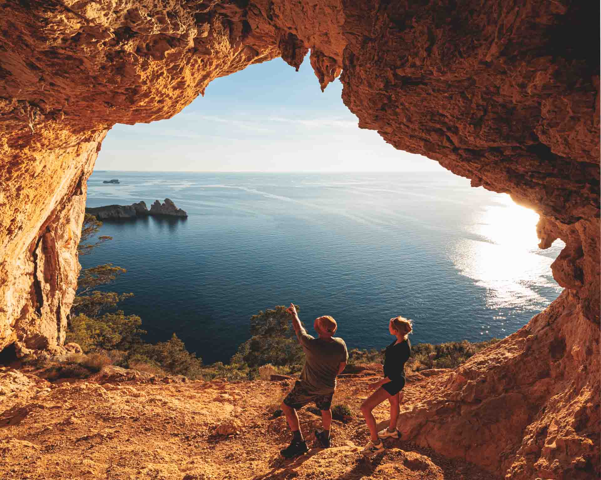 Hikers exploring massive natural stone arches and vaulted cliffs on Ibiza’s Cirque Hike, a remote trail known for its dramatic geological formations.