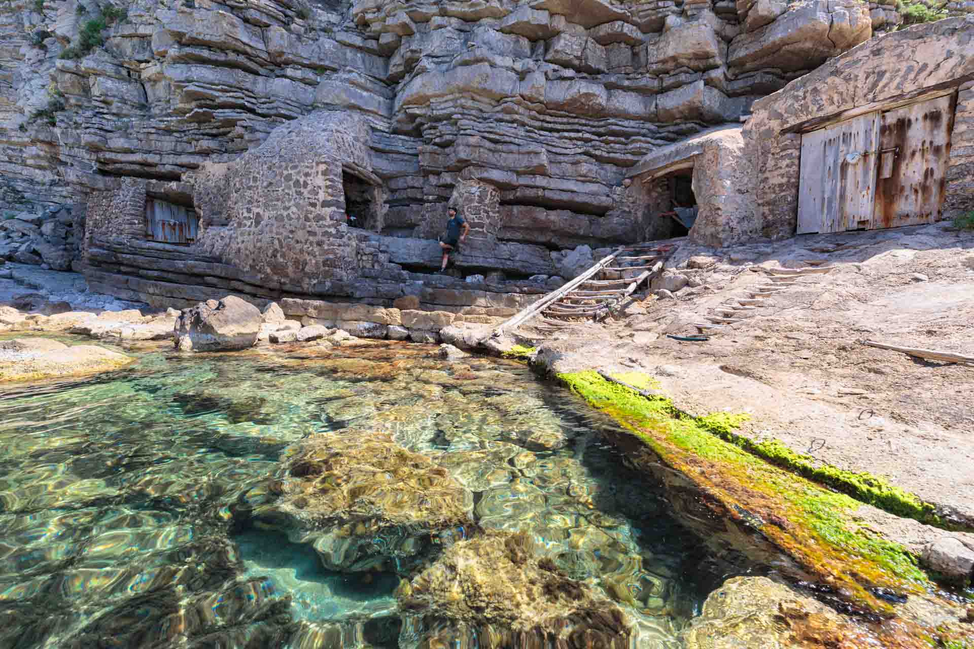 Remote pebble beach with emerald water and old fishermen’s huts, where hikers swim and relax surrounded by untouched nature and wild coastal beauty